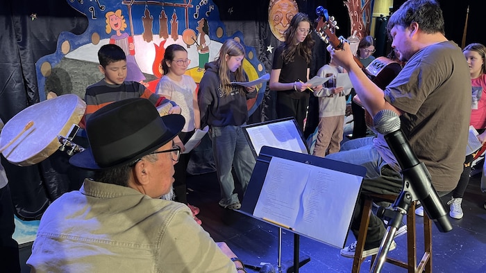 Deux artistes sont accompagnés par des élèves sur une scène.