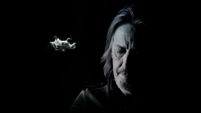 Serge Fiori sur un fond noir avec un artiste de cirque en chute libre.