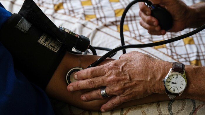 Plan rapproché des mains d'un docteur qui utilise un sphygmomanomètre pour mesurer la pression d'artérielle.