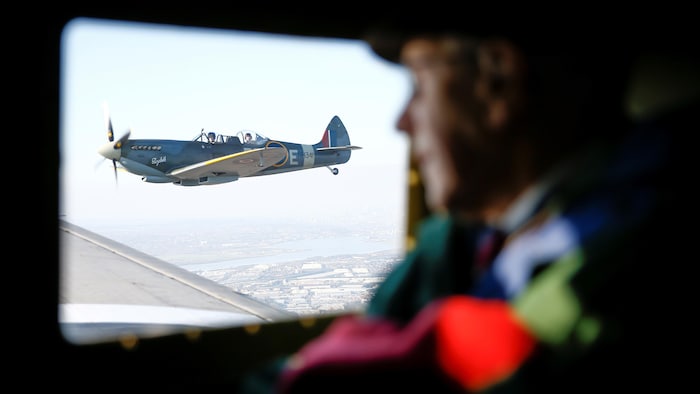Un vétéran, Roy Briggs, est assis dans un C 47 A Dakota et regarde par la fenêtre. Il voit passer un Spitfire.