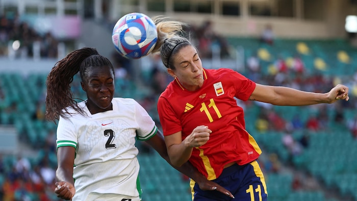 Michelle Alozie du Nigeria et Alexia Putellas d'Espagne tentent de frapper le ballon avec leur tête, pendant un match de soccer aux Jeux Olympiques de Paris 2024.