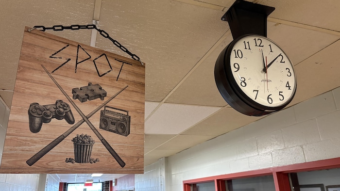 Une affiche est accrochée au plafond, près de la porte du local le «Spot».