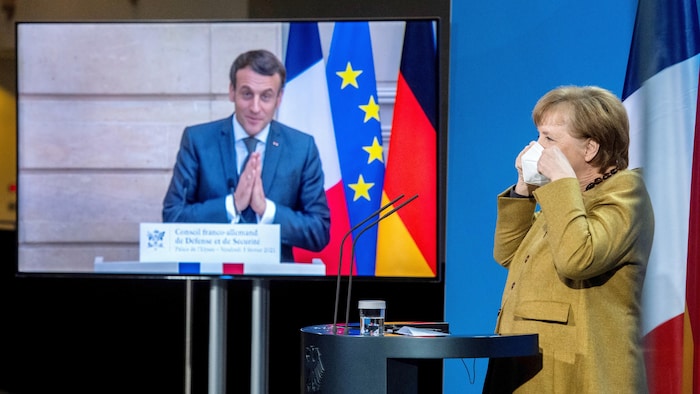 La chancelière Angel Merkel à Berlin et le président français Emmanuel Macron, dans un écran, participent à une conférence de presse.