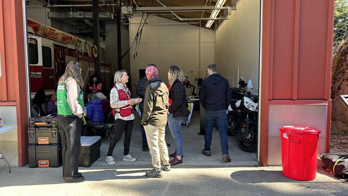 Des gens discute à l'entrée d'une caserne de pompiers.