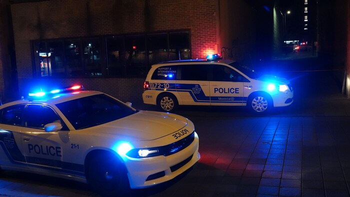 Des voitures de police avec les gyrophares allumés. 