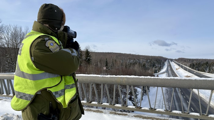 Un policier pointe un cinémomètre vers l'autoroute 10.