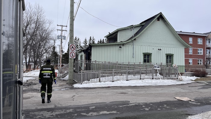 Un technicien en scène d'incendie circule dans une rue pour mener son enquête.