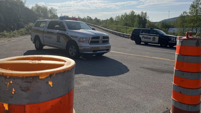 Deux véhicules de la Sûreté du Québec bloquent un chemin.