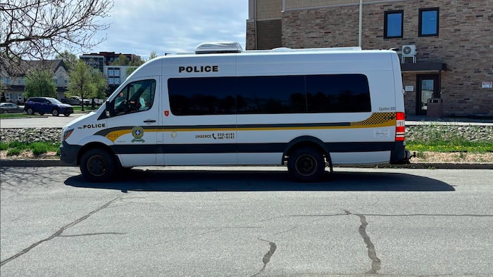 Une fourgonnette blanche lettrée Sûreté du Québec stationnée en bordure de rue