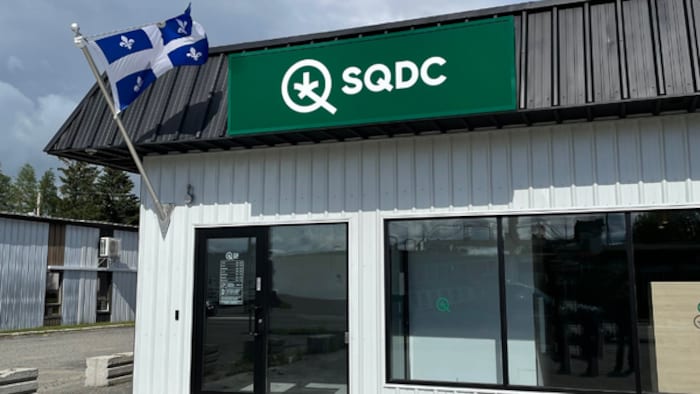 Bâtiment avec une porte d'entrée, la bannière de la SQDC et le drapeau du Québec.