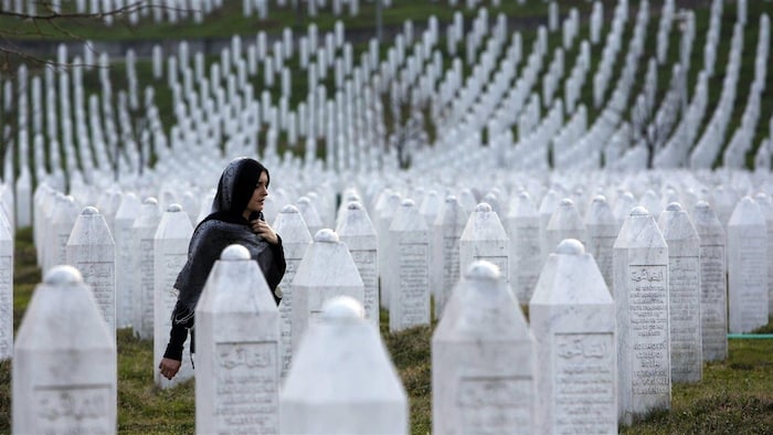 Une femme marche parmi les pierres tombales au Centre Potocari, près de Srebrenica.