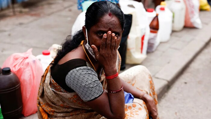 A woman waits to buy kerosene Colombo, Sri Lanka, a country that's been an early victim of rising debt loads. Economist fear something similar will happen to other countries as payments loans denominated in U.S. dollars become unaffordable. (Dinuka Liyanawatte/Reuters)
