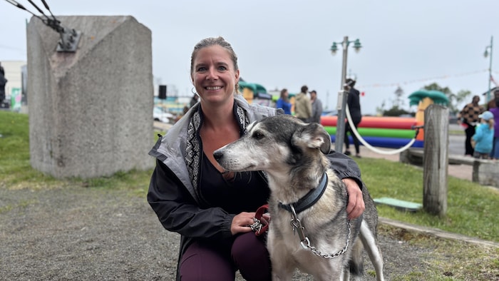 Stacy Leblanc squatting with a dog by his side.  munning nationalism canada festival sept-îles