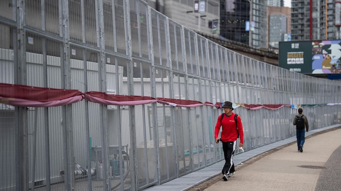 Un homme marche le long d'une longue clôture.