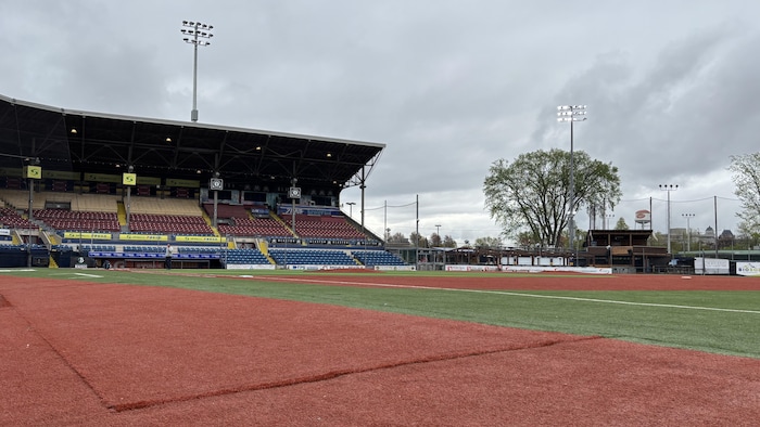 Les lumières du système d'éclairage sont allumées en plein jour autour d'un terrain de baseball désert.