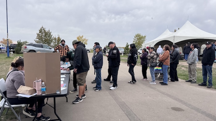 Des personnes font la queue devant une table.