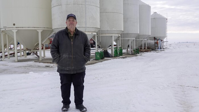 Un homme devant des silos de graines.