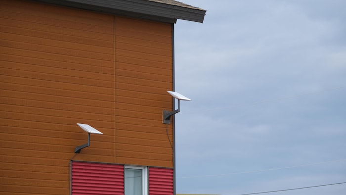 Photo extérieure de deux antennes Starlink sur le côté d'une maison. 
