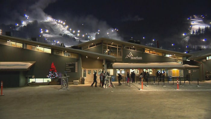 Des skieurs se présentent aux guichets d'une station de ski. 