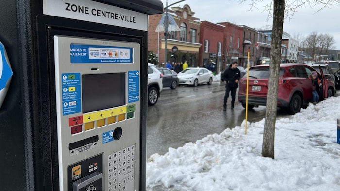 Un horodateur et des véhicules stationnés.