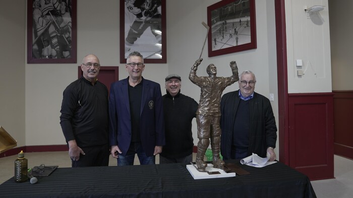 Wayne Bozzer, Paul Harrison, Mike Mulryan et Ed Pupich posent aux côtés d'une nouvelle statue du Père Costello.