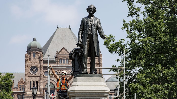 Des travailleurs enlèves les échafaudrafes autour de la statue de John A. Macdonald le 11 juin 2025.