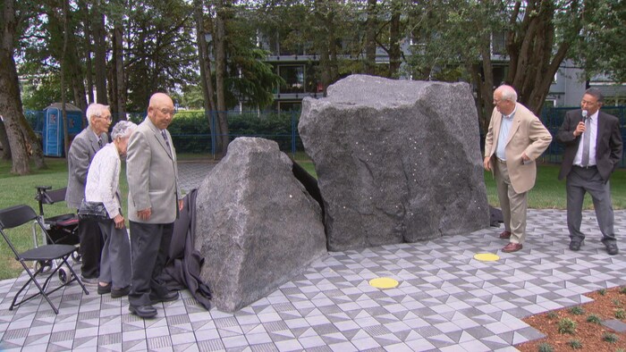 Un grupo de hombres rodea una nueva escultura en roca.