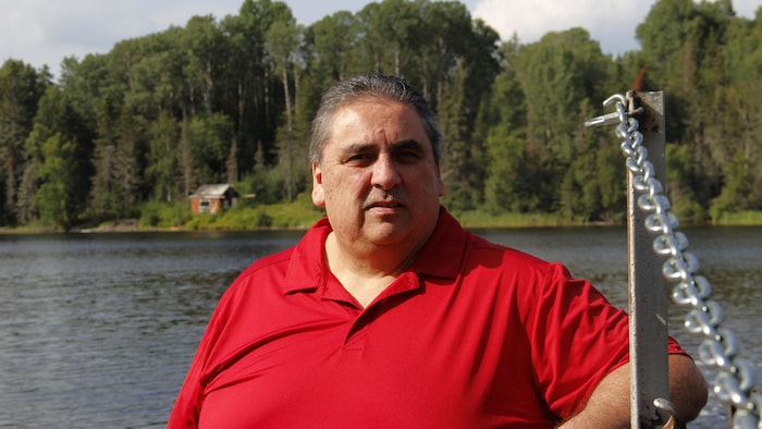 Un homme en chandail rouge au bord de la rivière des Outaouais.
