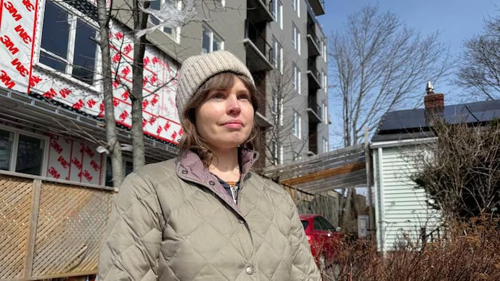 Une trentenaire en portrait devant un immeuble en construction.