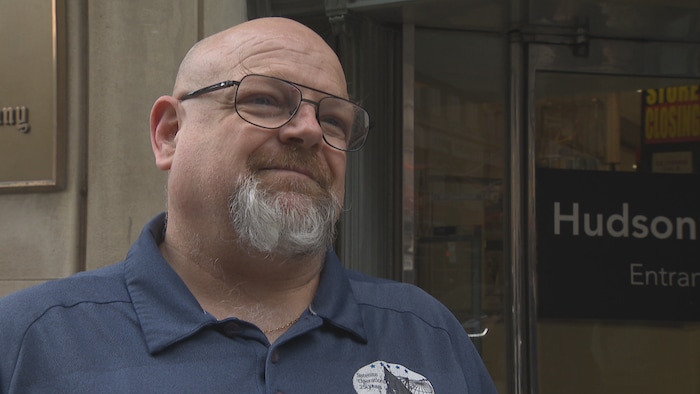 A man in front of the entrance to La Baie d'Hudson Shop.