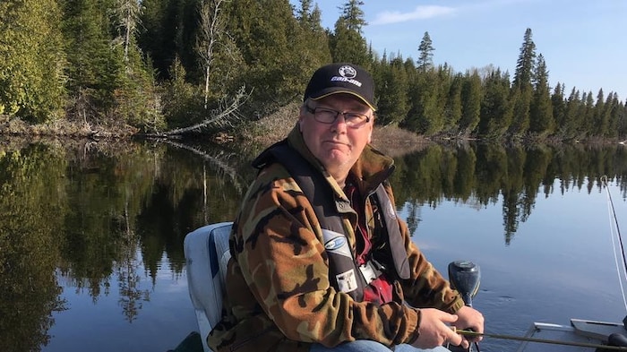 Stéphane Brière en chaloupe sur un lac, pêchant.