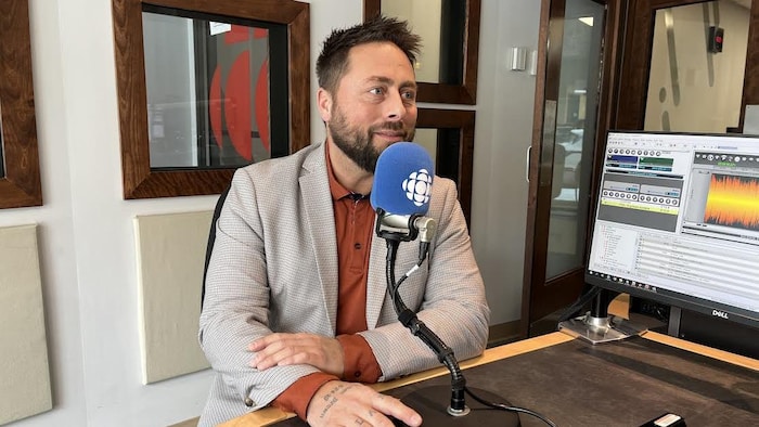 Stéphane Brown, assis derrière en micro, en entrevue dans un studio de Radio-Canada.