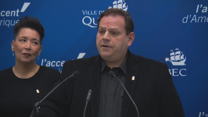 Um homme regarde la caméra en point de presse. 