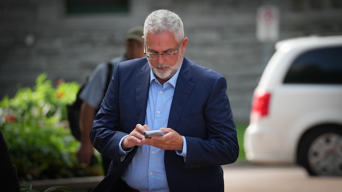 L'ancien avocat Stéphane Langlois marche avec son téléphone en direction du palais de justice d'Ottawa.
