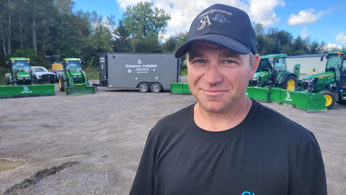 Stéphane Lemieux dans un stationnement où se trouvent de nombreux tracteurs.