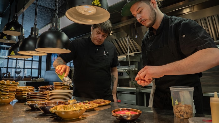 Deux hommes habillés en noir travaillent dans une cuisine de restaurant.