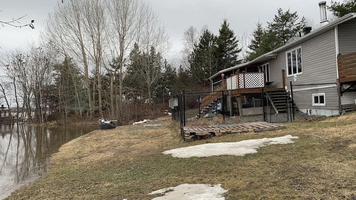 Vue sur une maison, dont le terrain est en partie inondé.