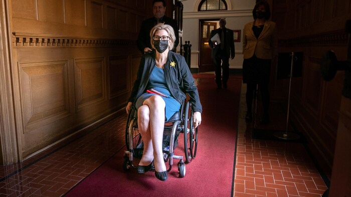 Stephanie Cadieux dans un fauteuil roulant, portant un masque.