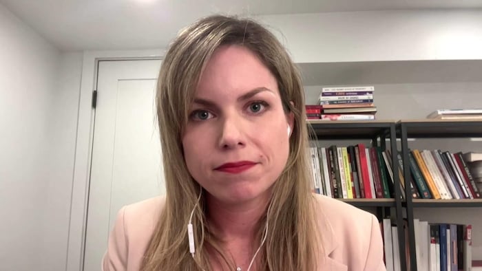 Stéphanie Chouinard assise devant une bibliothèque aux étagères remplies de livres.