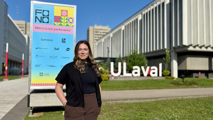 Stéphanie Couture pose devant une affiche du festival Fono sur le campus de l'Université Laval, en été.