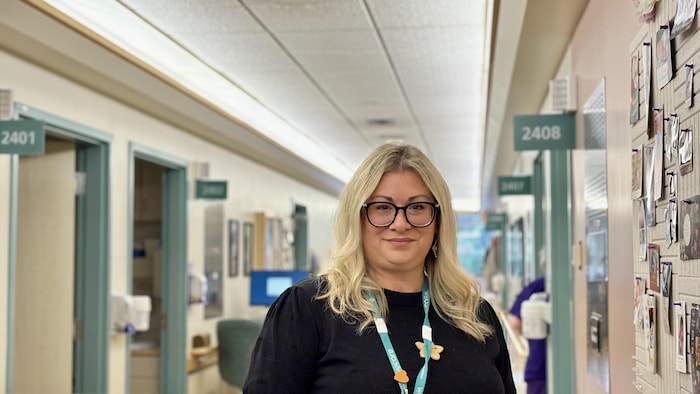 Une femme sourit devant les chambres individuelles à l'unité de naissances de l'hôpital de Whitehorse.