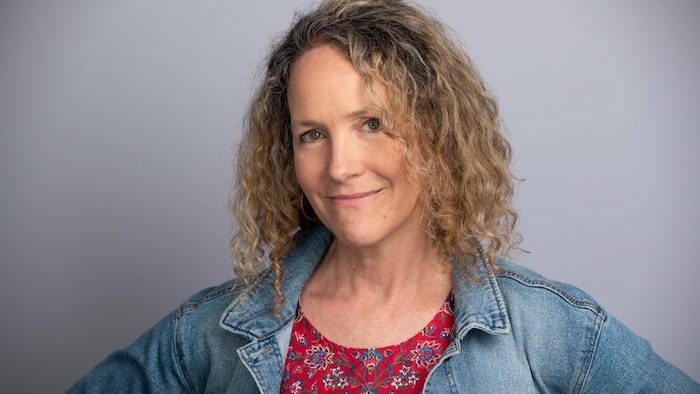 A woman with slightly curly hair, wearing a jeans jacket, poses, hands on the hips. no need authorization train ai