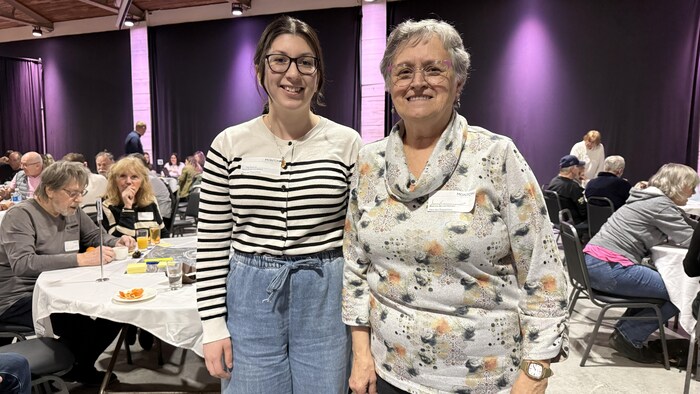 Deux femmes sont debout et sourient à la caméra.