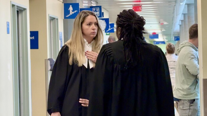 Les deux avocates vêtues de leur toge discutent dans le corridor.