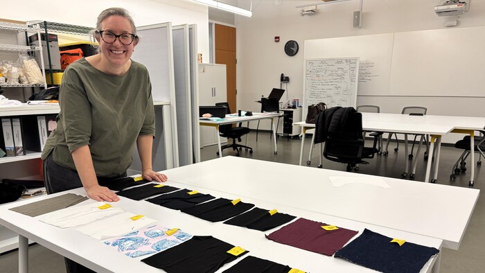 Stephanie Phillips, debout devant une table regroupant plusieurs échantillons de tissu.