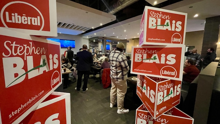 Des affiches électorales au nom de Stephen Blais devant des gens assis dans un restaurant.