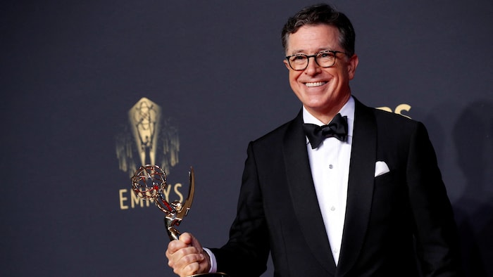 Stephen Colbert tout sourire brandit un trophée Emmy.