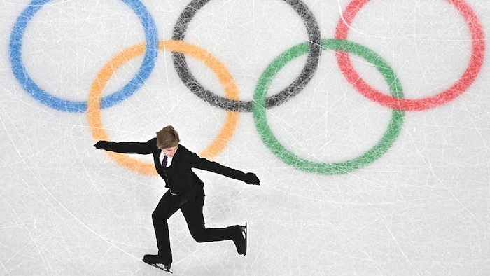 Il effectue une figure artistique près des anneaux olympiques peints sur la glace.
