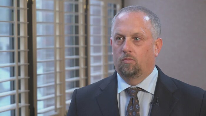 Stephen Laskowski, debout près d'une fenêtre, donne une entrevue.