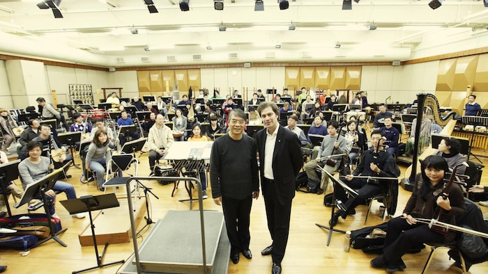 Portraits de deux hommes debout devant des musiciens assis.